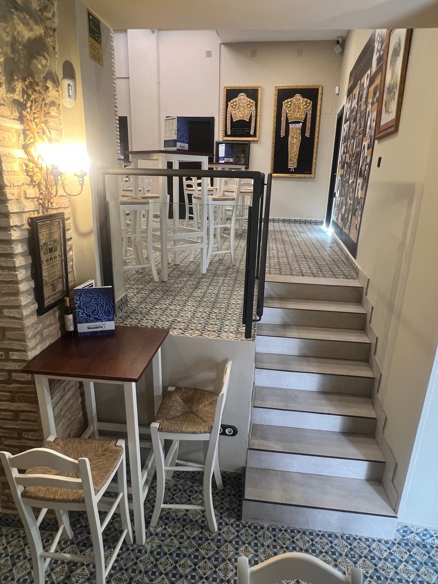 Interior Taberna Ágora — escalera y trajes de luces enmarcados